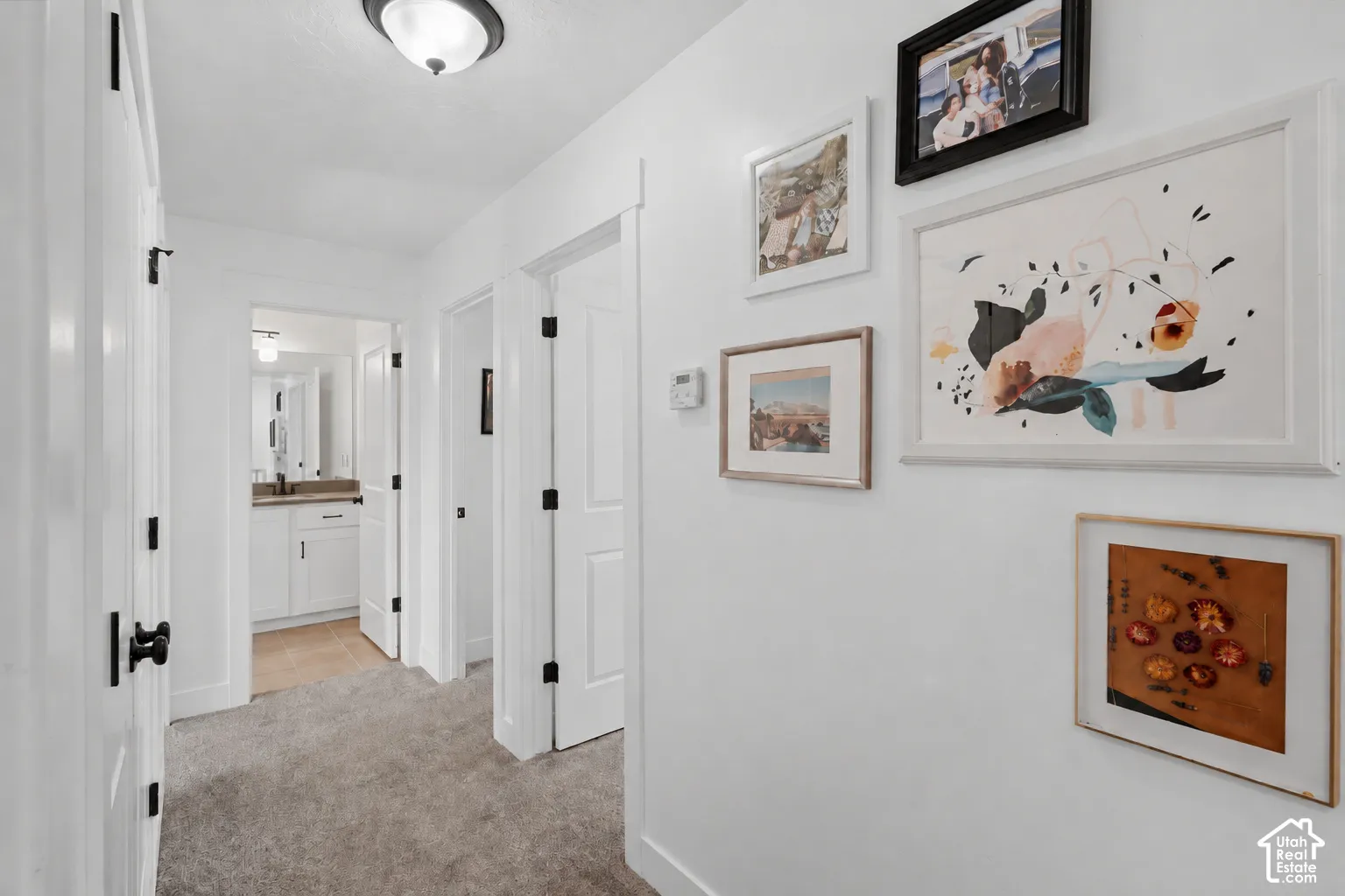 Hallway featuring a ceiling-mounted light fixture, white interior doors, and gray carpeting