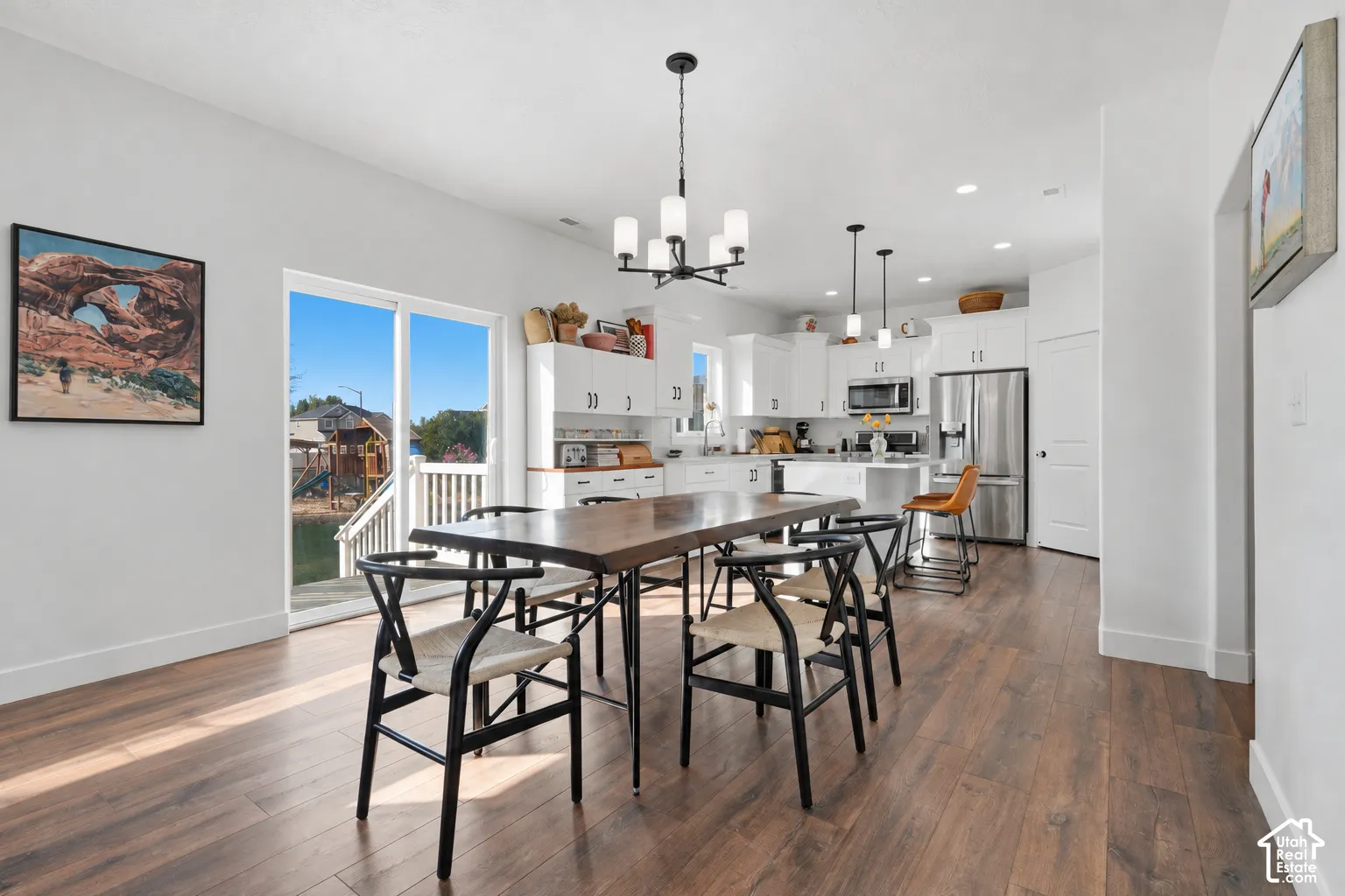 Open-concept living space with wood-finish flooring, white cabinetry, and stainless steel appliances