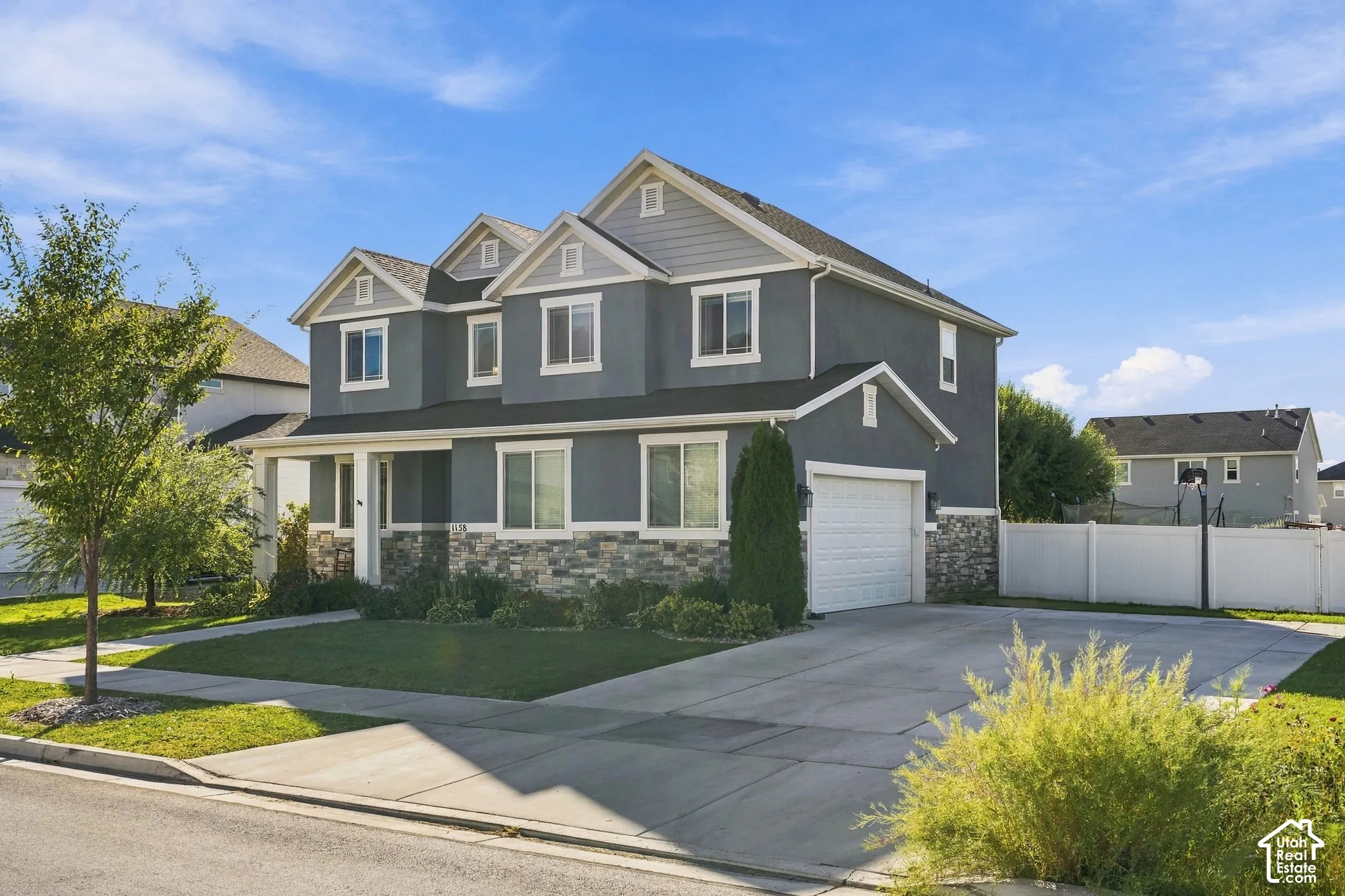 Two-story exterior with a covered entry, stone veneer accents, an attached garage, and a concrete driveway