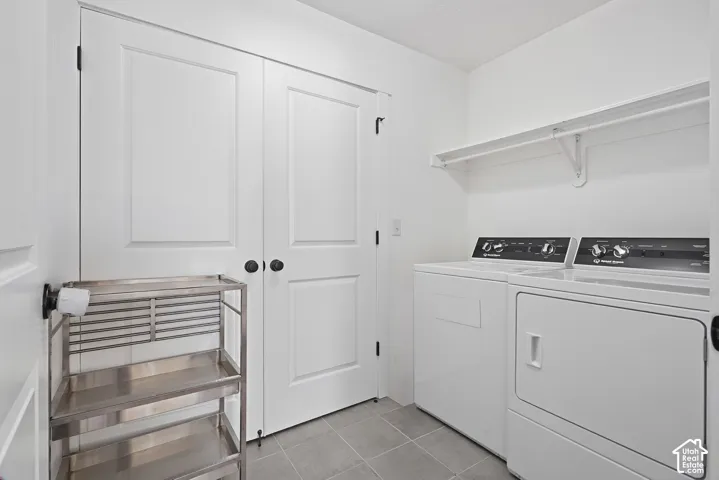 Laundry area featuring a built-in shelving unit, white panel doors with black hardware, and tile flooring