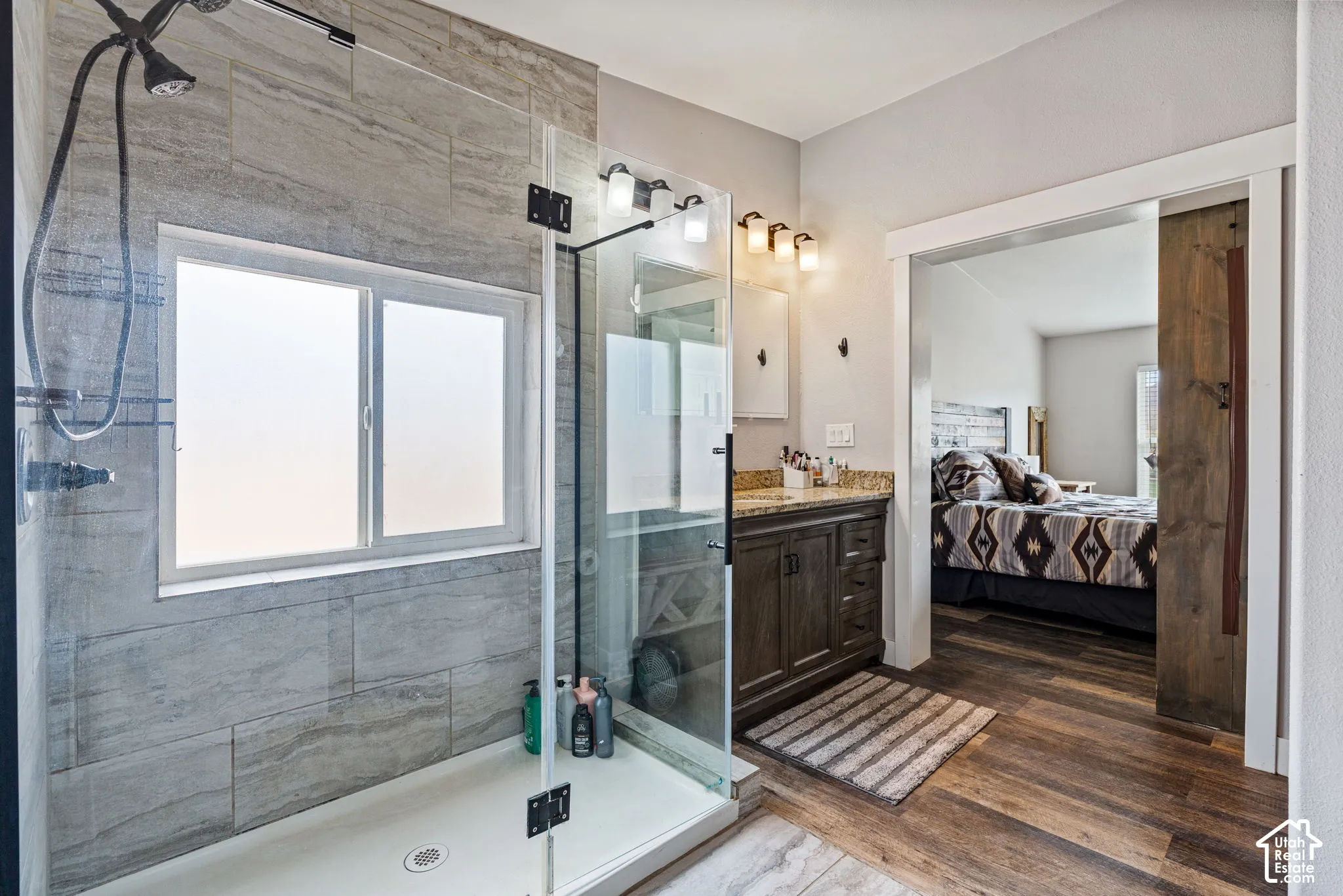 Glass-enclosed shower with gray tile surround and frosted window