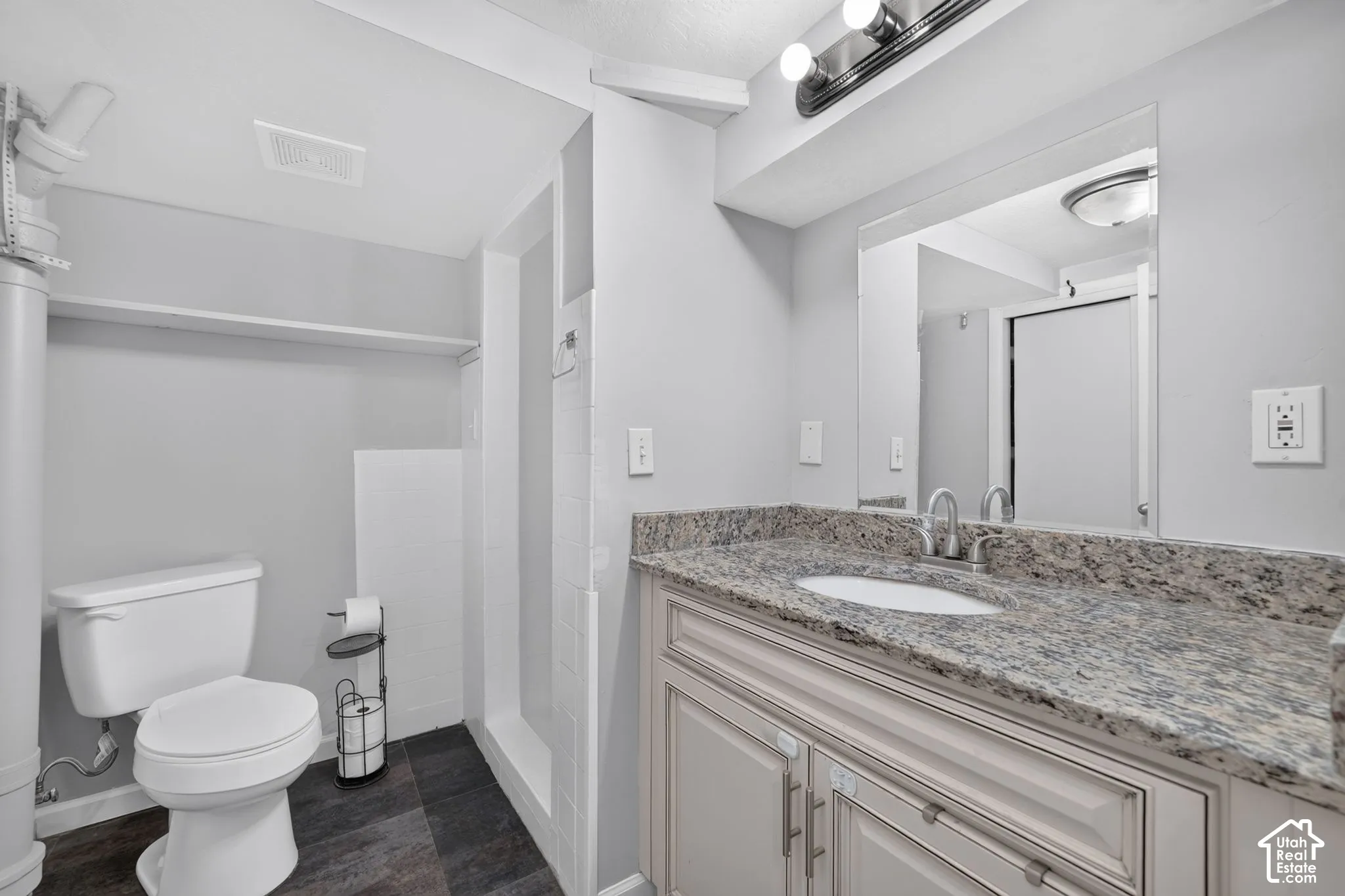 Vanity with a light-colored stone countertop, undermount sink, and brushed nickel faucet