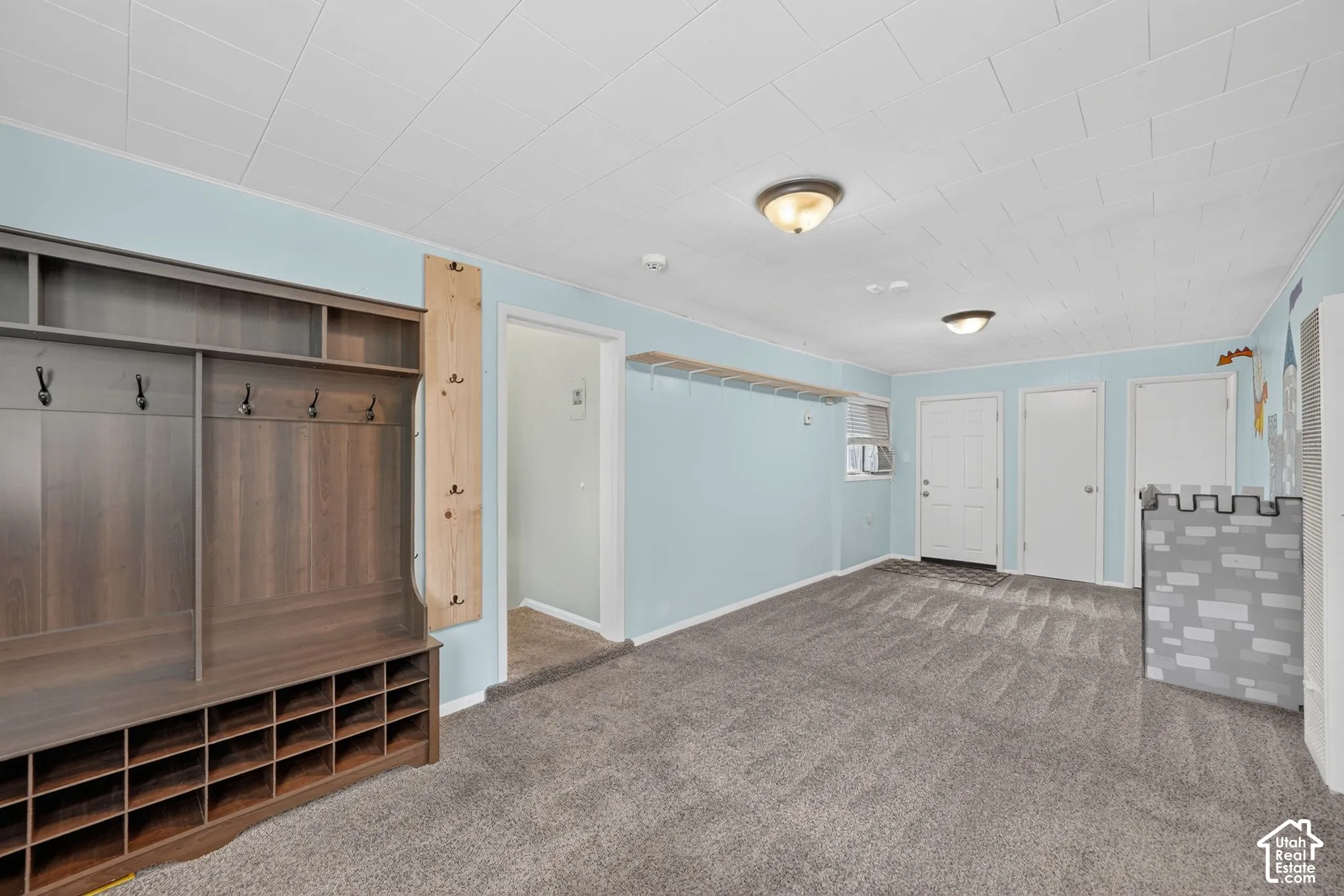 Wall-to-wall carpeting, two ceiling-mounted light fixtures, built-in shelving with coat hooks, and multiple doors