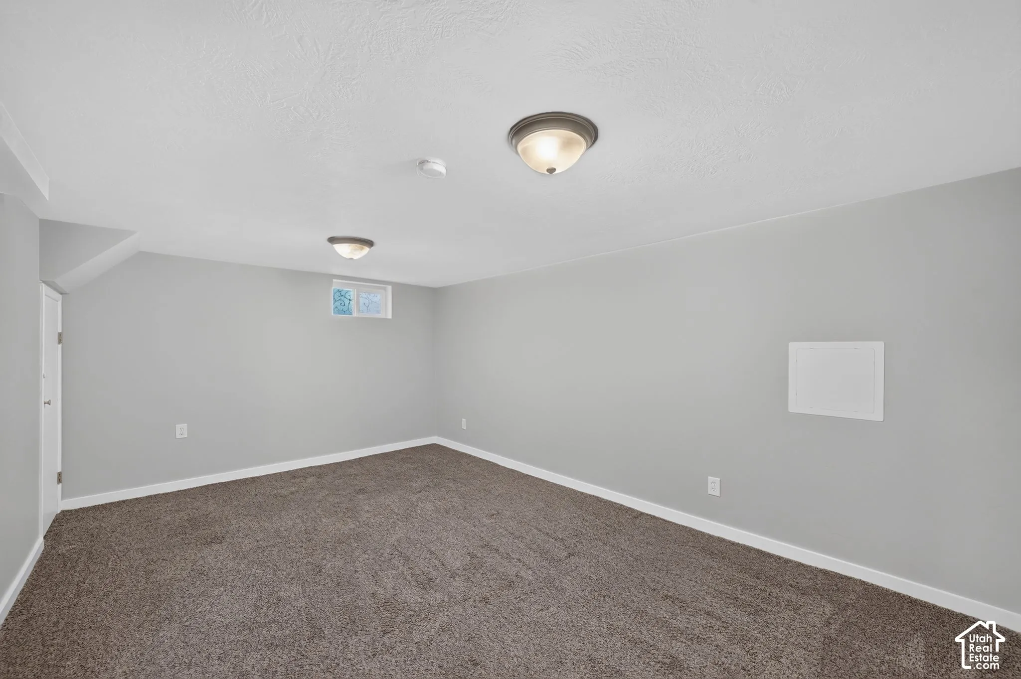 Neutral gray wall paint, textured ceiling, flush-mount ceiling lighting, window, and wall-to-wall carpeting