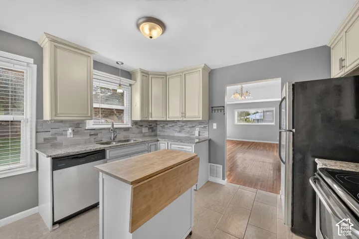 Kitchen featuring light cabinetry, granite countertops, a stainless steel dishwasher, tile flooring, and a portable island with a wood-finish top
