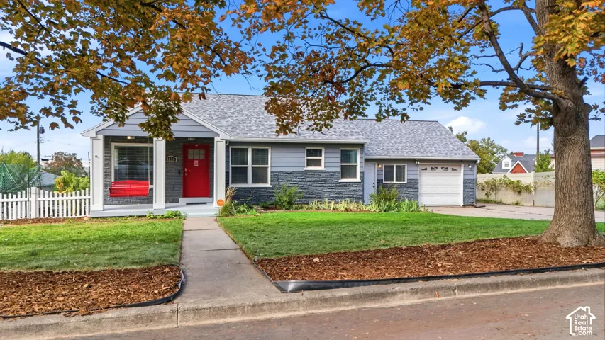 Exterior featuring gray siding, stone accent facade, white picket fencing, and an attached garage