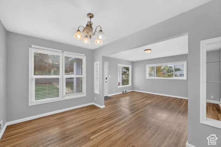 Hardwood-finish flooring, multiple windows providing ample light, a decorative chandelier, and recessed lighting