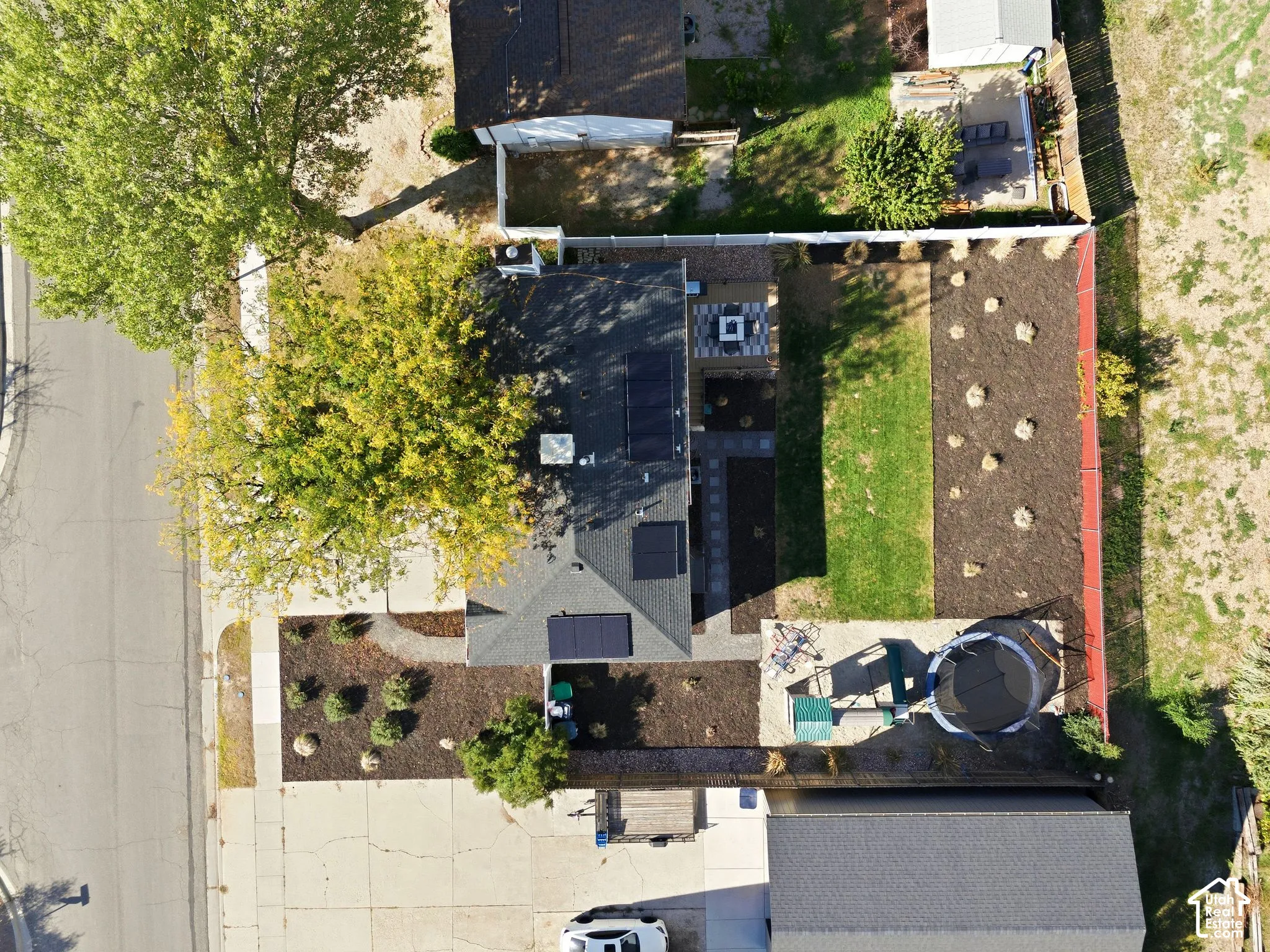 Expansive backyard featuring a manicured lawn, established trees, and a concrete patio