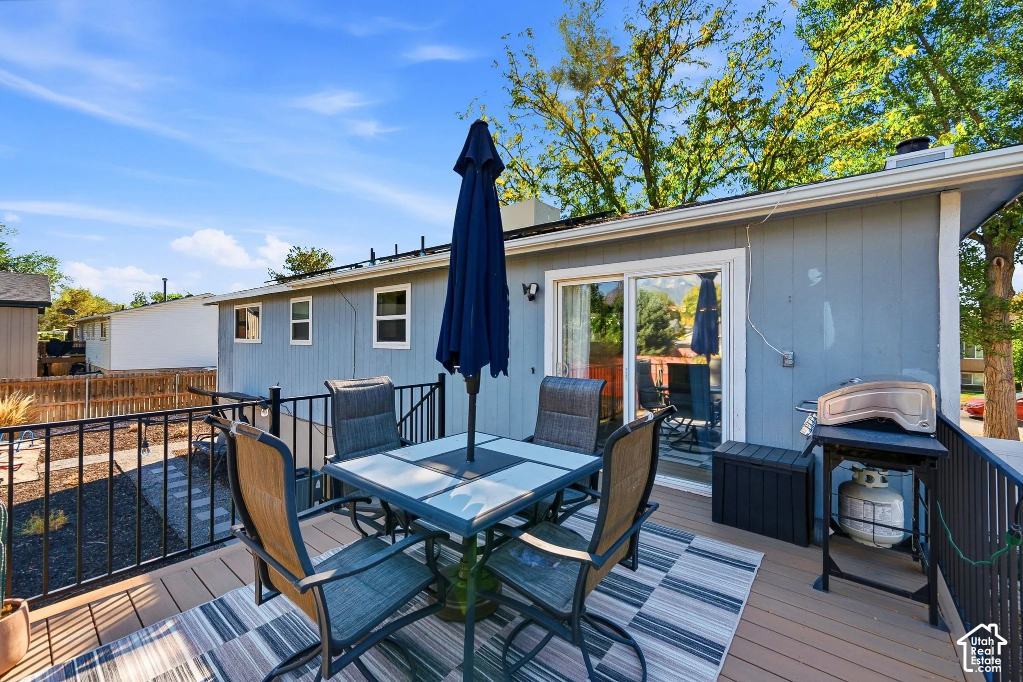 Composite wood deck with black metal railing, sliding glass door, and a gray-painted exterior