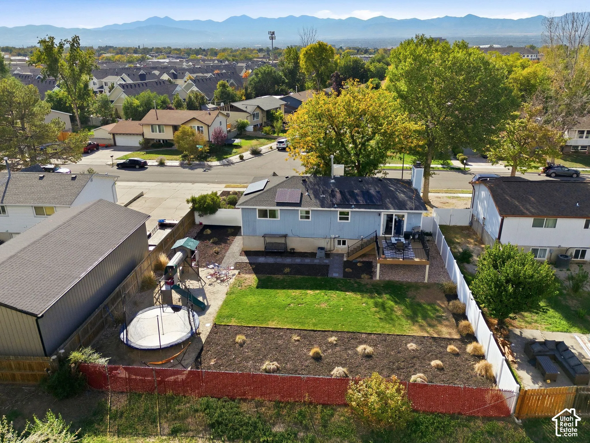Expansive backyard featuring a manicured lawn, dedicated planting beds, and a multi-level deck