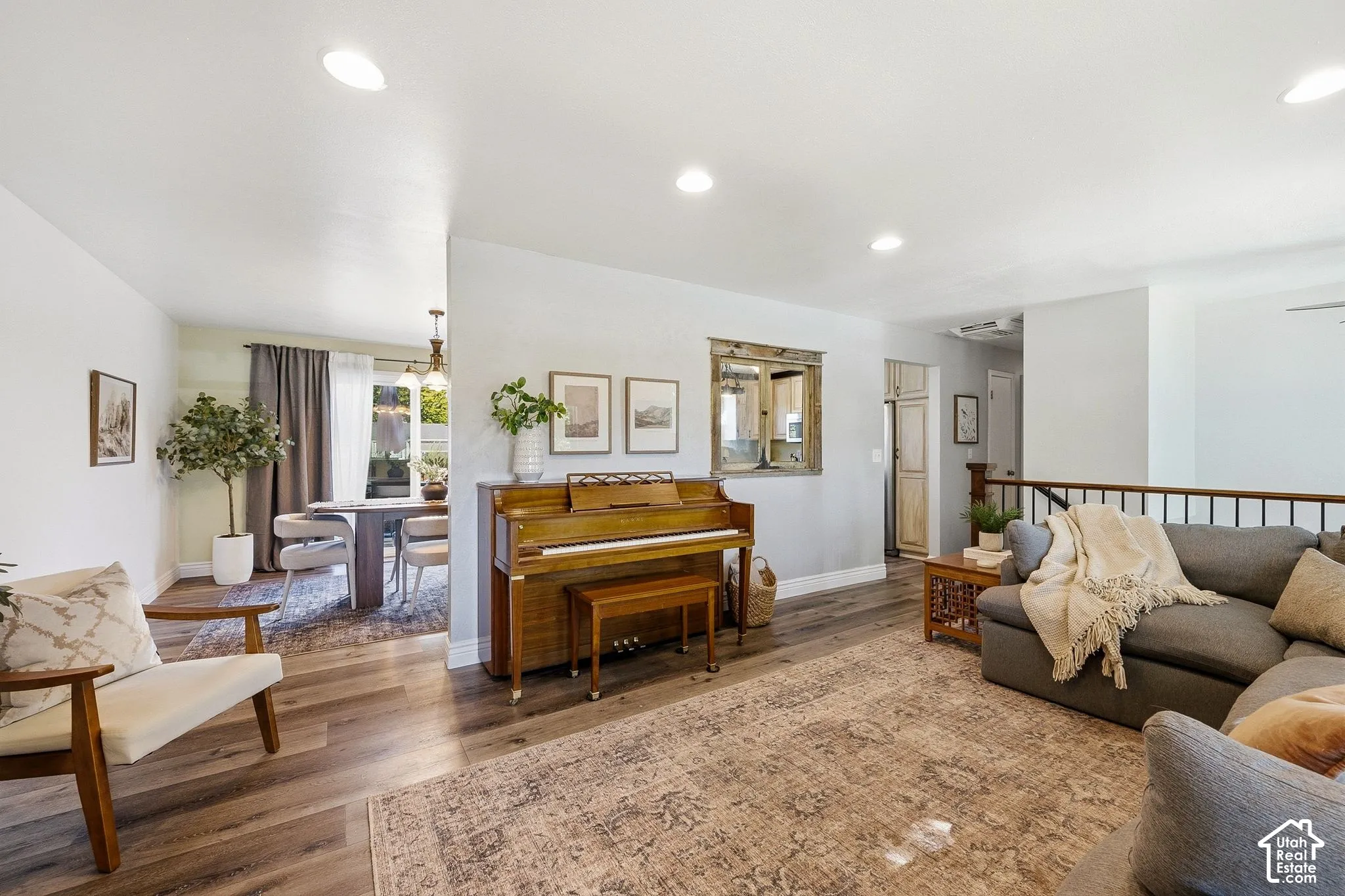 Recessed lighting, wood-finish flooring, half-wall with wood railing, built-in storage cabinet, and a dedicated dining space