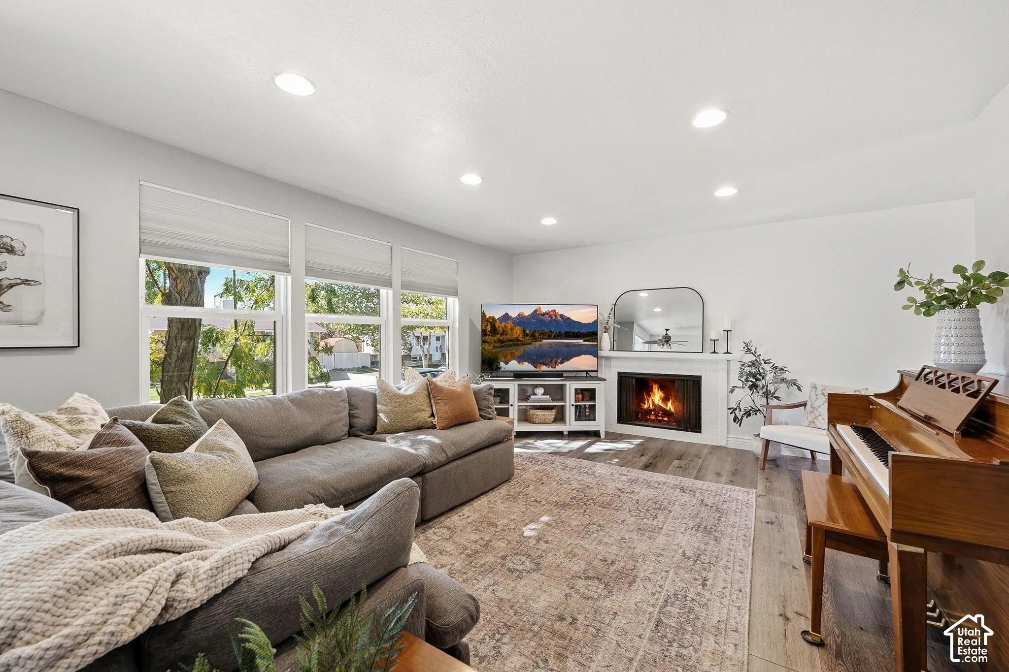Living area featuring wood-finish flooring, recessed lighting, and large windows with privacy blinds