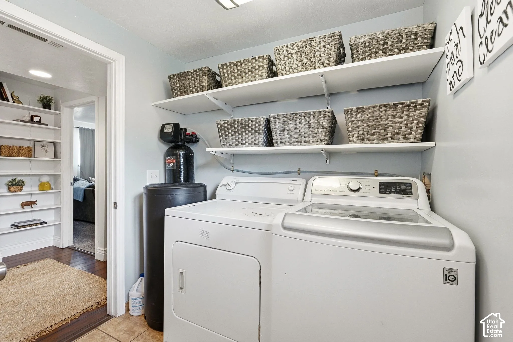 Laundry area featuring a top-load washing machine, front-load dryer, and wall-mounted shelving
