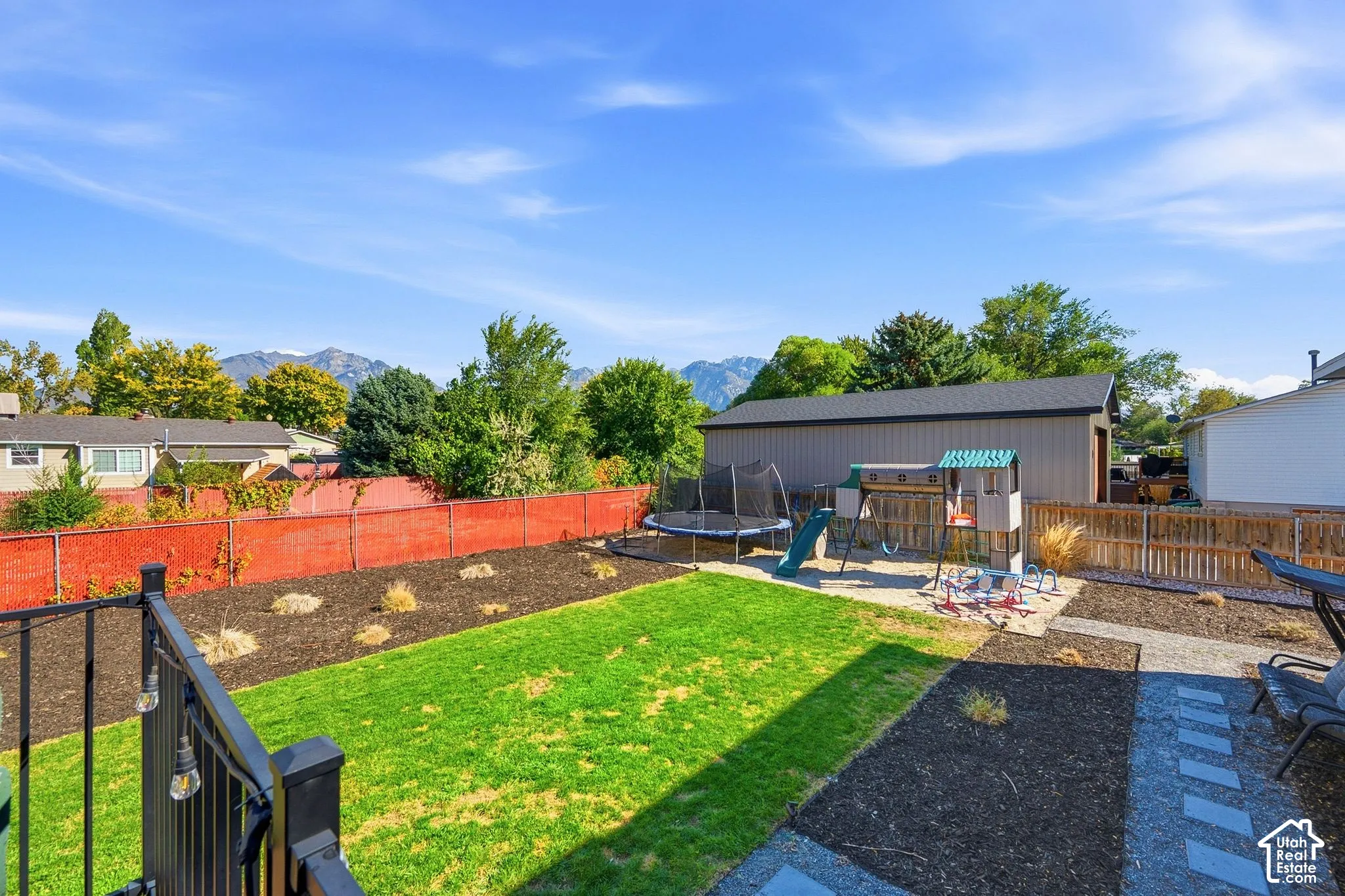 Expansive backyard featuring a green lawn, dark wood chip landscaping, and a substantial storage shed with a dark roof