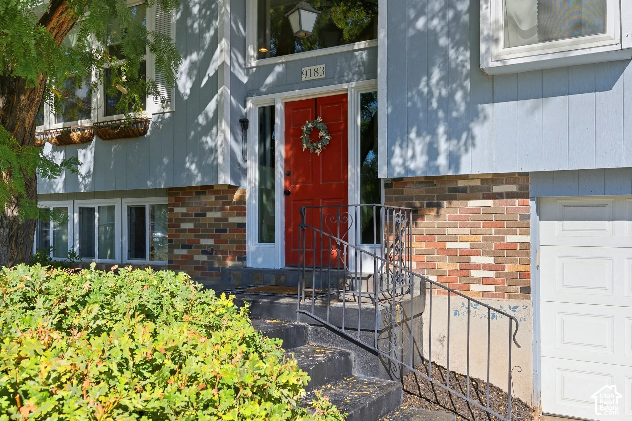 Split-level residence featuring a vibrant red entry door, multi-toned brick facade, and integrated garage access