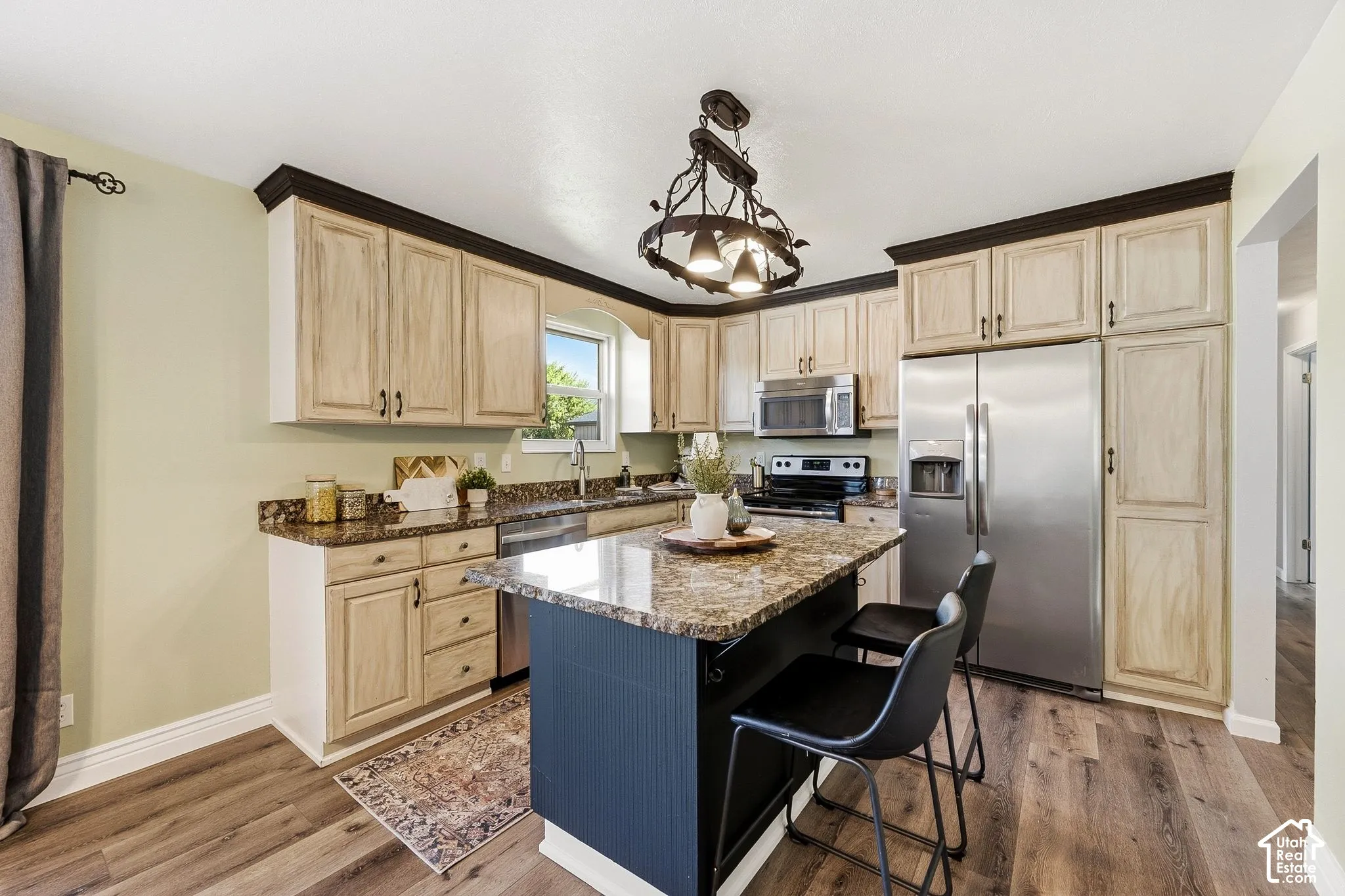 Kitchen featuring wood-finish flooring, an island with countertop, stainless steel appliances, and ample cabinetry