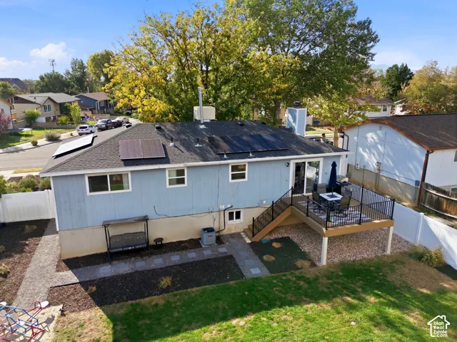 Rear exterior with siding, solar panels, and a wood-finish deck with black railing