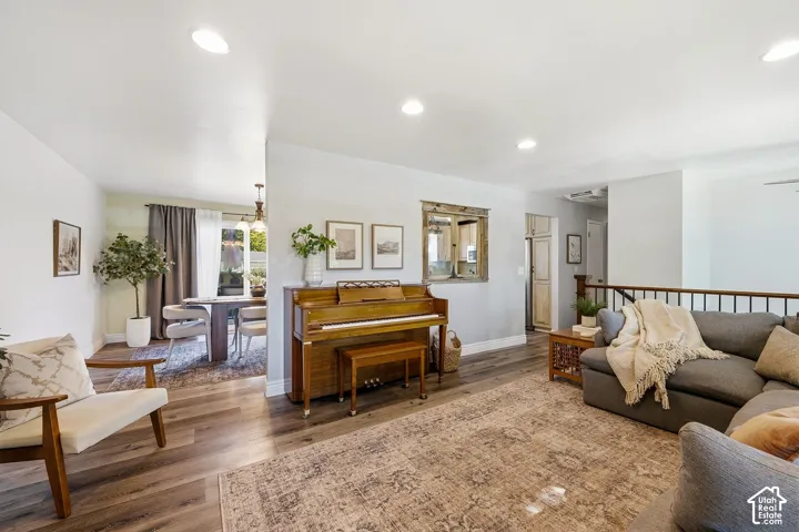 Recessed lighting, wood-finish flooring, half-wall with wood railing, built-in storage cabinet, and a dedicated dining space