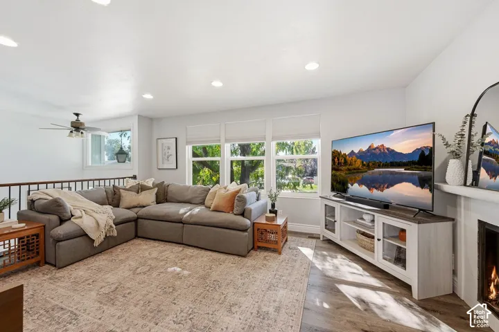 Recessed lighting, wood-finish flooring, multiple windows, built-in fireplace, and a ceiling fan