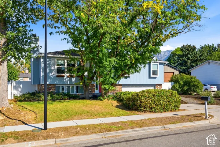 Split-level residence featuring light blue siding, a red entry door, and a two-car garage