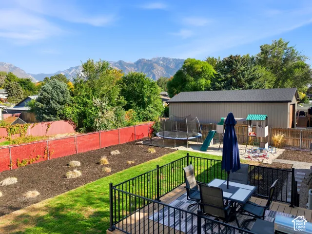 Expansive backyard featuring a wood-finish deck, black metal railing, and a large storage shed