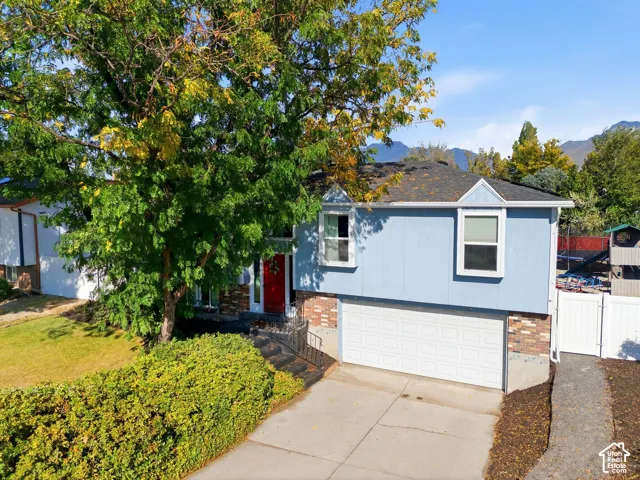 Split-level residence featuring light blue siding with brick accents and a prominent red entry door