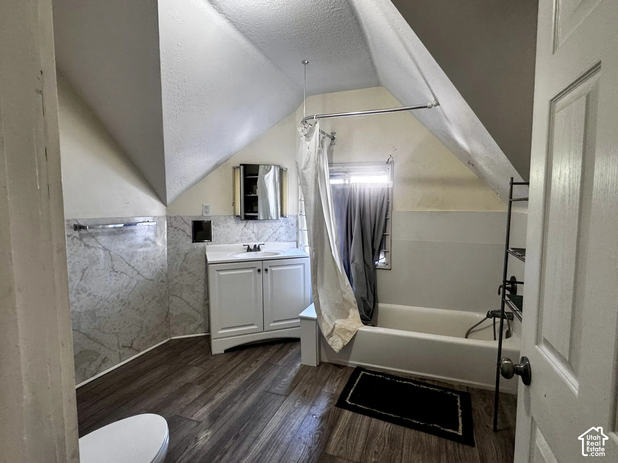 Bathroom featuring sloped ceilings, wood-finish flooring, and a built-in bathtub