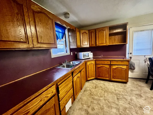 Kitchen featuring wood-finish cabinetry, a double basin sink, and a built-in range