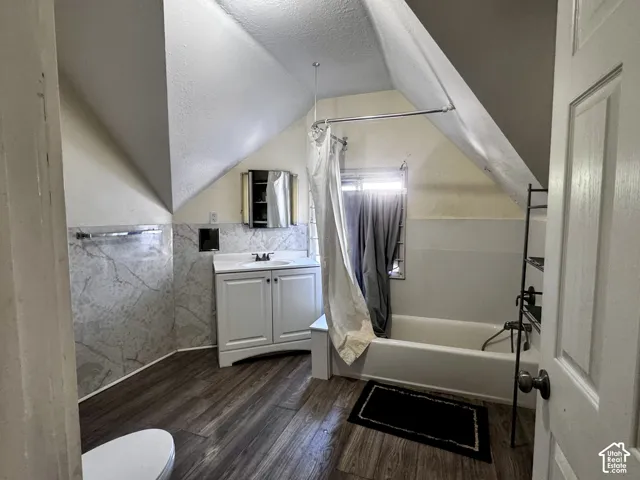 Bathroom featuring sloped ceilings, wood-finish flooring, and a built-in bathtub
