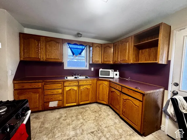 Kitchen featuring wood-finish cabinetry, a double basin sink, and a built-in range