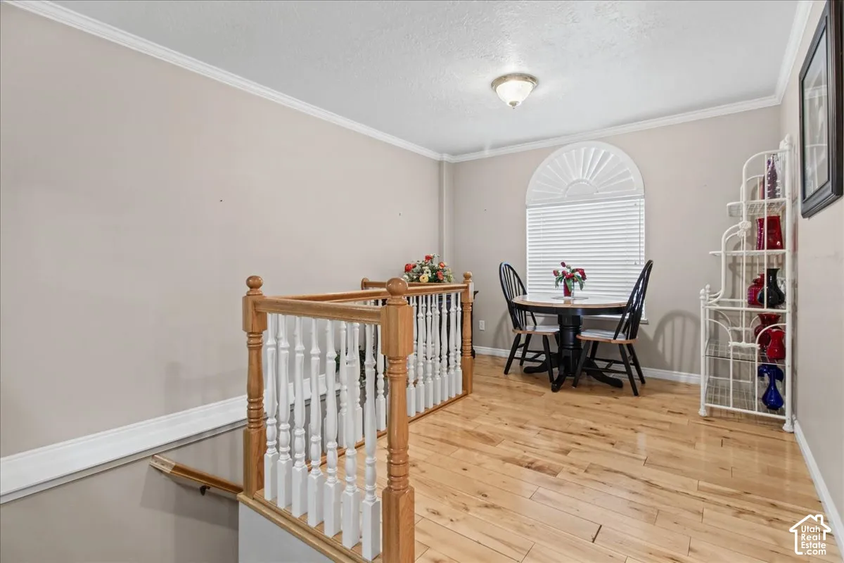 Hardwood flooring, painted walls, crown molding, arched window with blinds, and a semi-flush mount light fixture