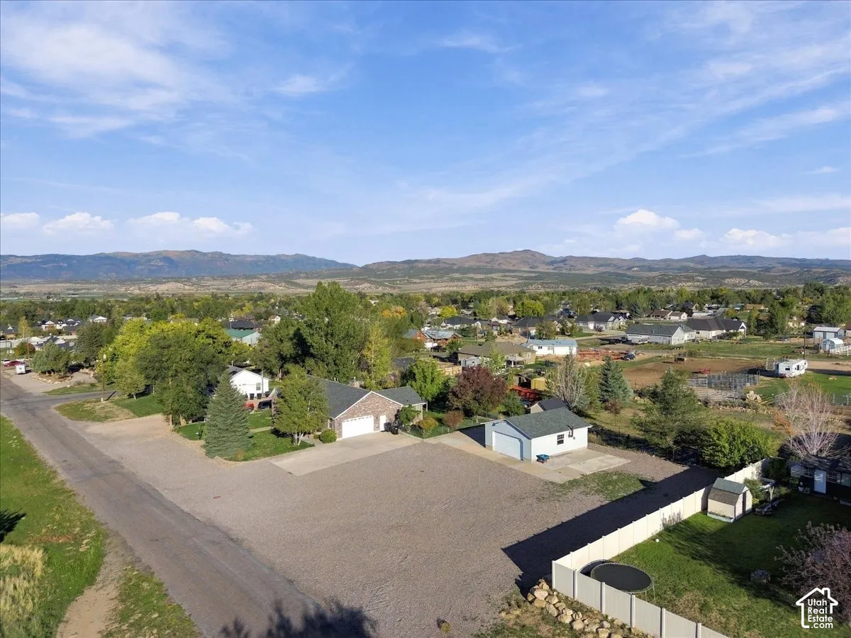Expansive property with a gravel lot, mature trees, and a distant mountain backdrop