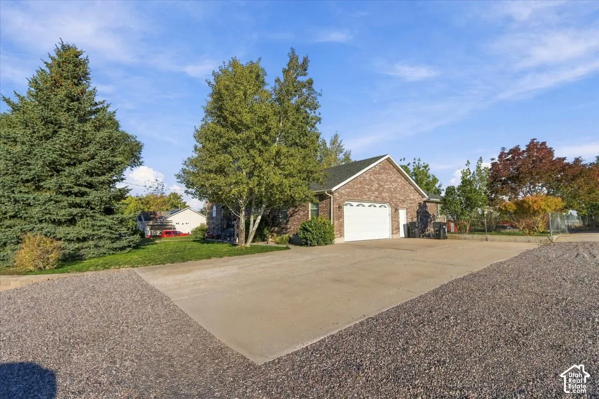 Brick exterior with white garage doors, asphalt shingle roof, and concrete driveway