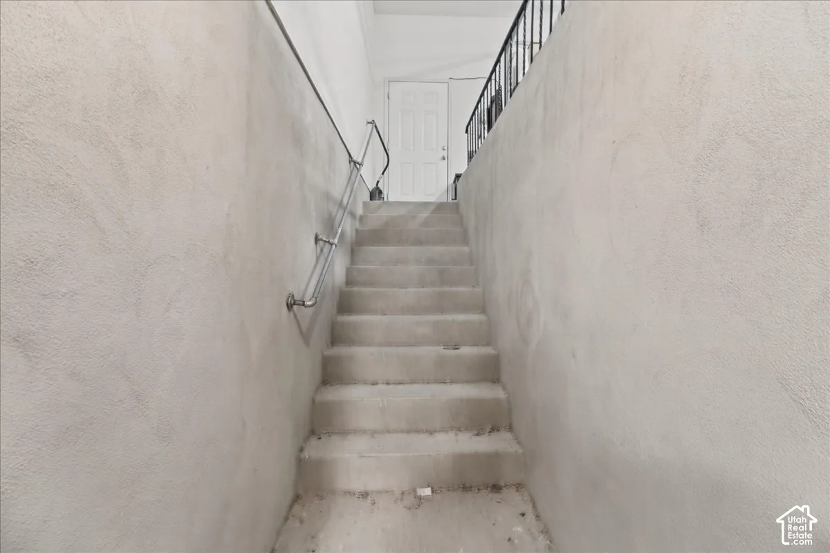 Concrete staircase with a metal handrail and textured wall finish