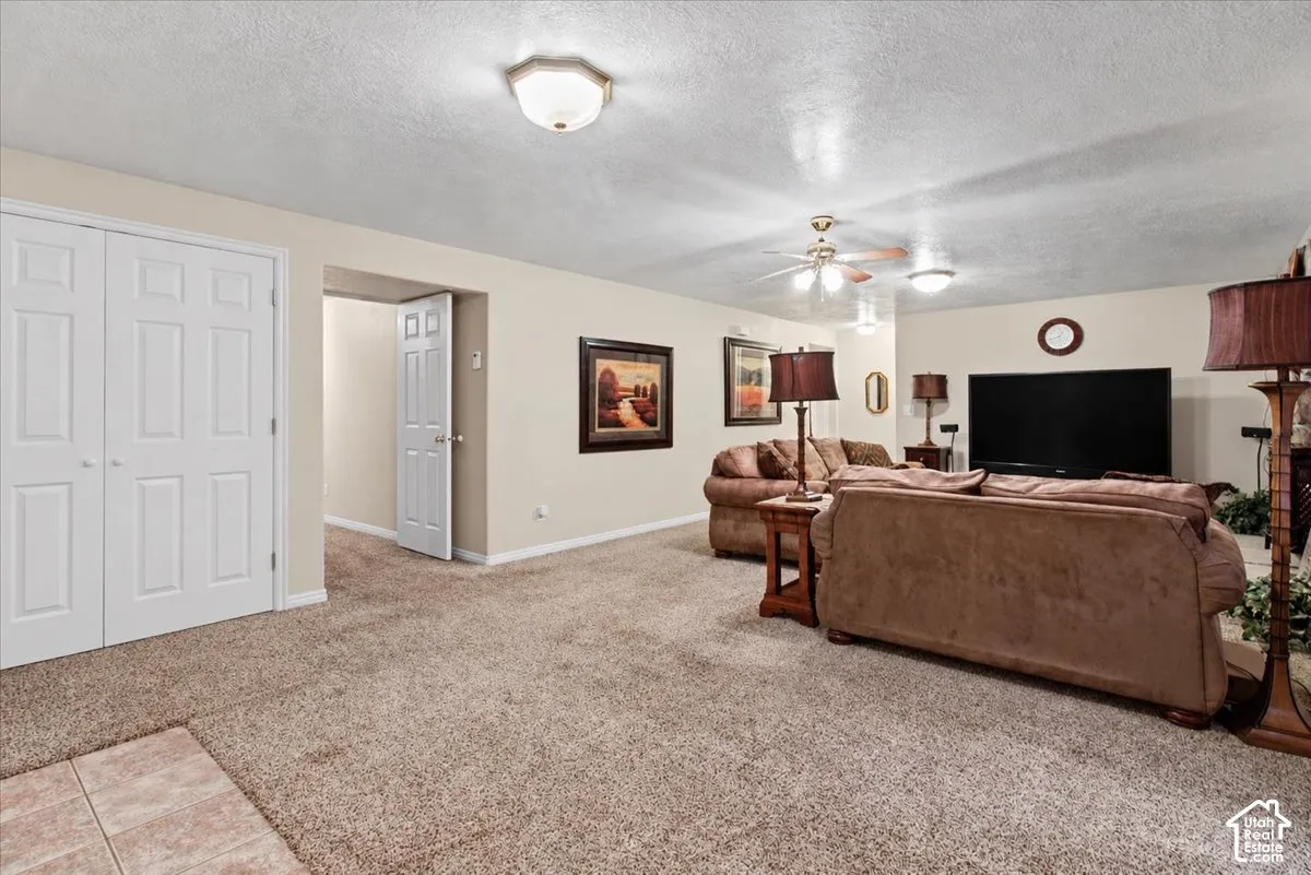Carpeted living area featuring a ceiling fan, recessed lighting, and a white paneled door