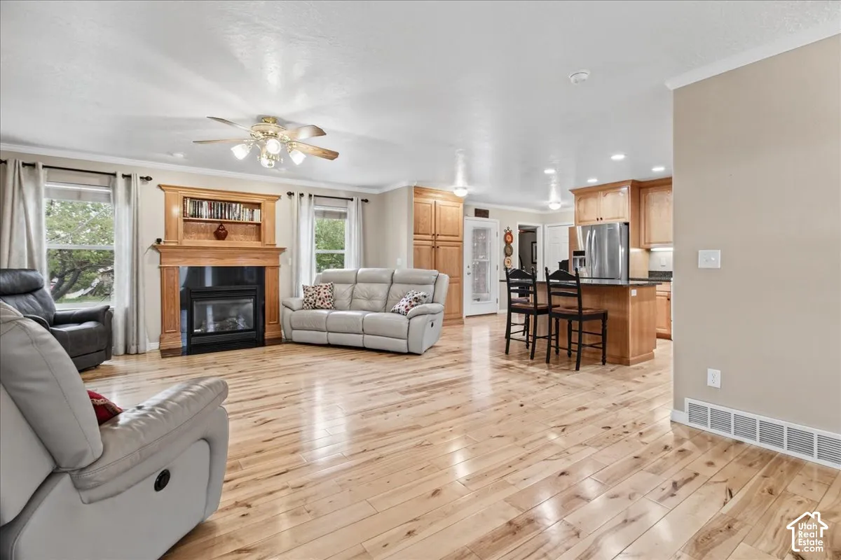 Hardwood flooring throughout, a built-in fireplace with wood mantel, recessed lighting, and a ceiling fan
