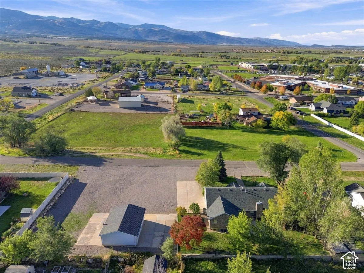 Expansive lot featuring a main residence with a dark shingle roof, a detached structure with a dark shingle roof, and a gravel driveway
