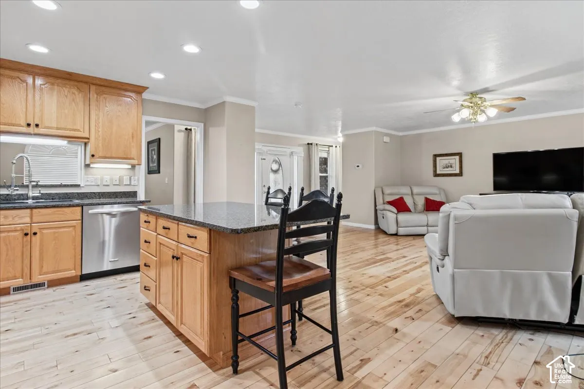 Kitchen island with granite-style countertop, wood-finish cabinetry, stainless-steel dishwasher, and wood-finish flooring throughout