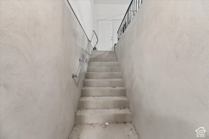 Concrete staircase with a metal handrail and textured wall finish