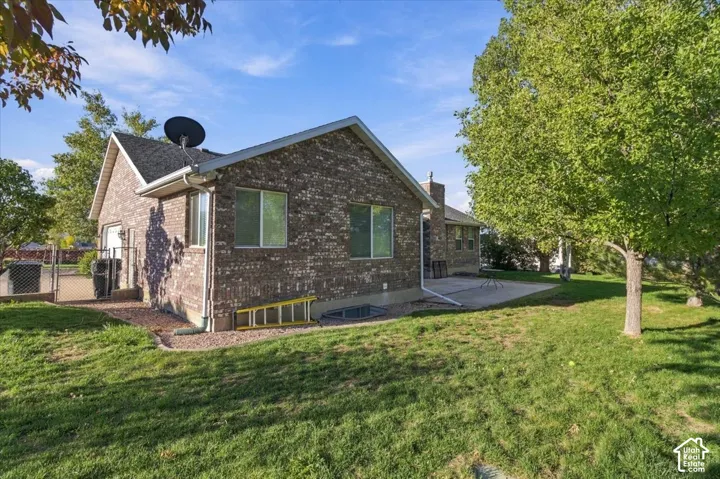 Brick exterior with white window frames, a black shingled roof, and a concrete patio