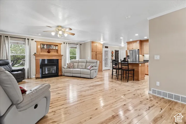 Hardwood flooring throughout, a built-in fireplace with wood mantel, recessed lighting, and a ceiling fan