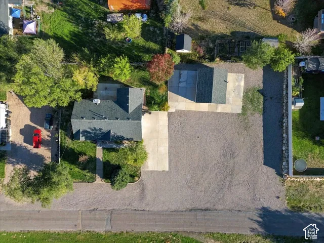 Expansive gravel lot with a dedicated concrete driveway and a detached structure