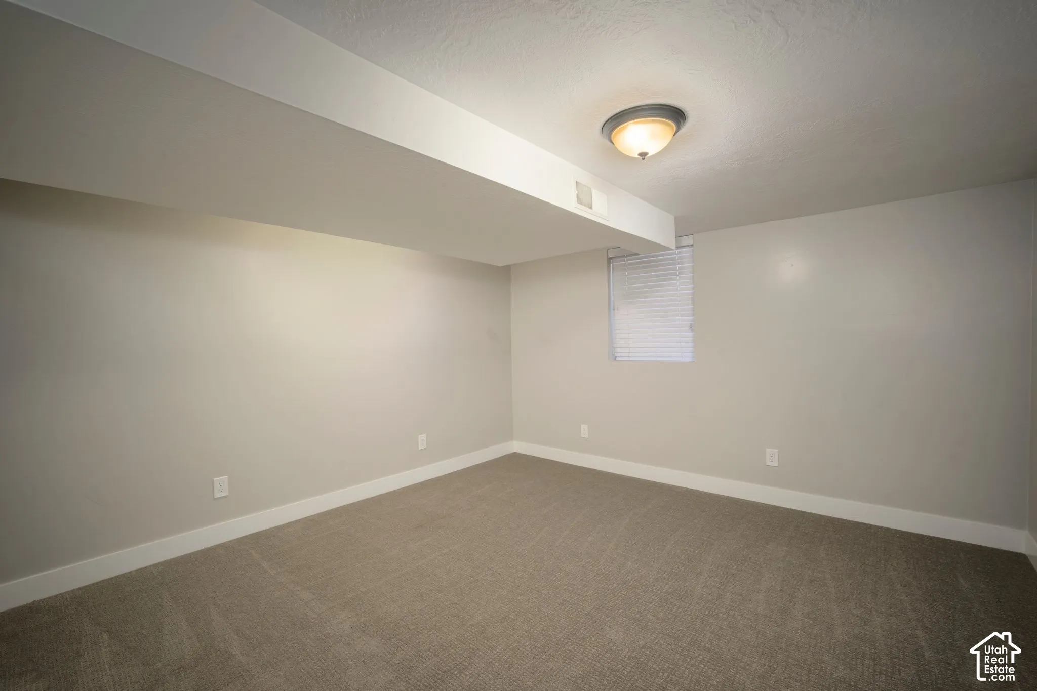 Recessed ceiling light fixture, neutral wall paint, carpeted flooring, window with blinds