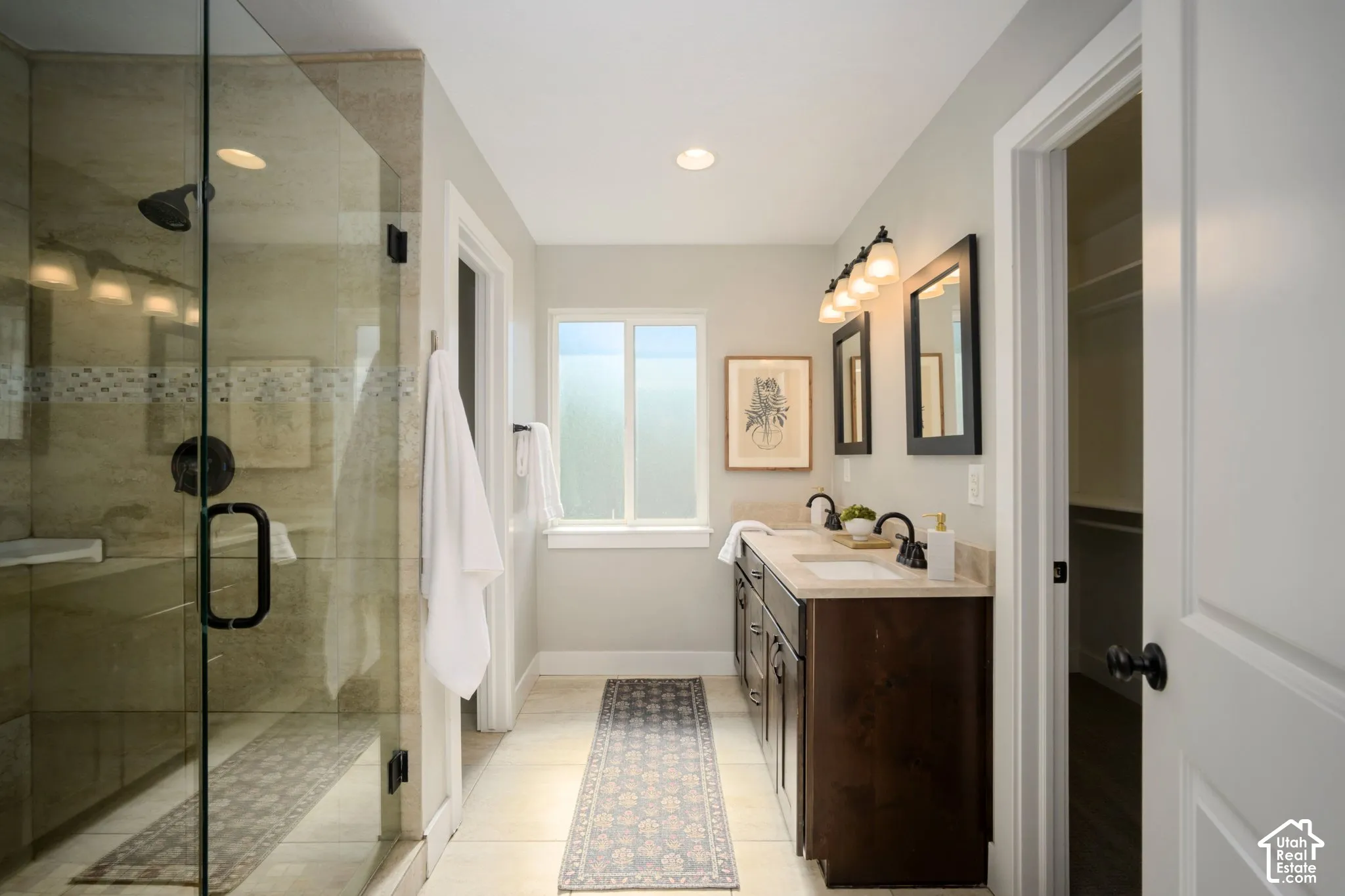 Primary Suite. Glass-enclosed shower with a bench, dual vanity with undermount sinks, and a framed window