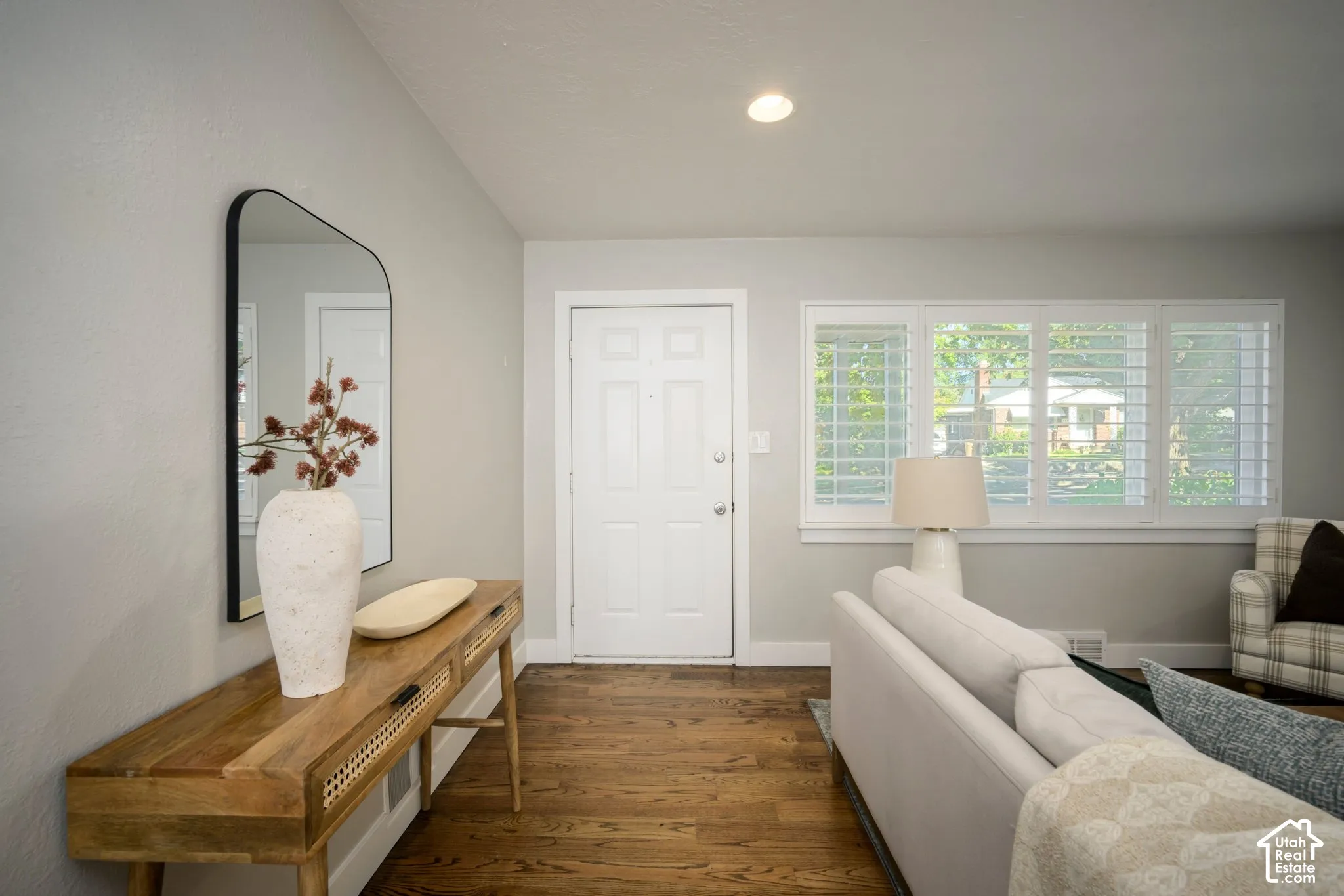 Hardwood flooring with a light gray wall finish, recessed lighting, and a window featuring white plantation shutters