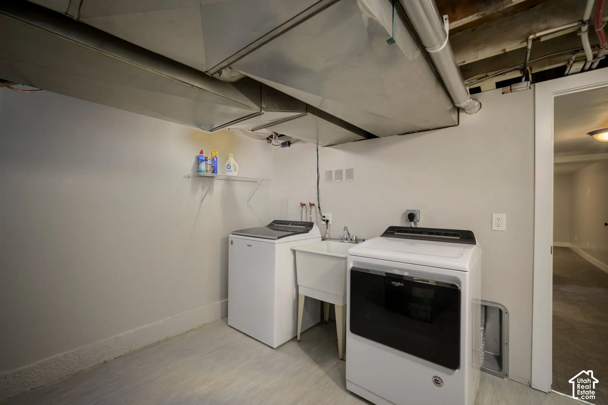 Utility area featuring a utility sink, light gray walls, and light-toned flooring