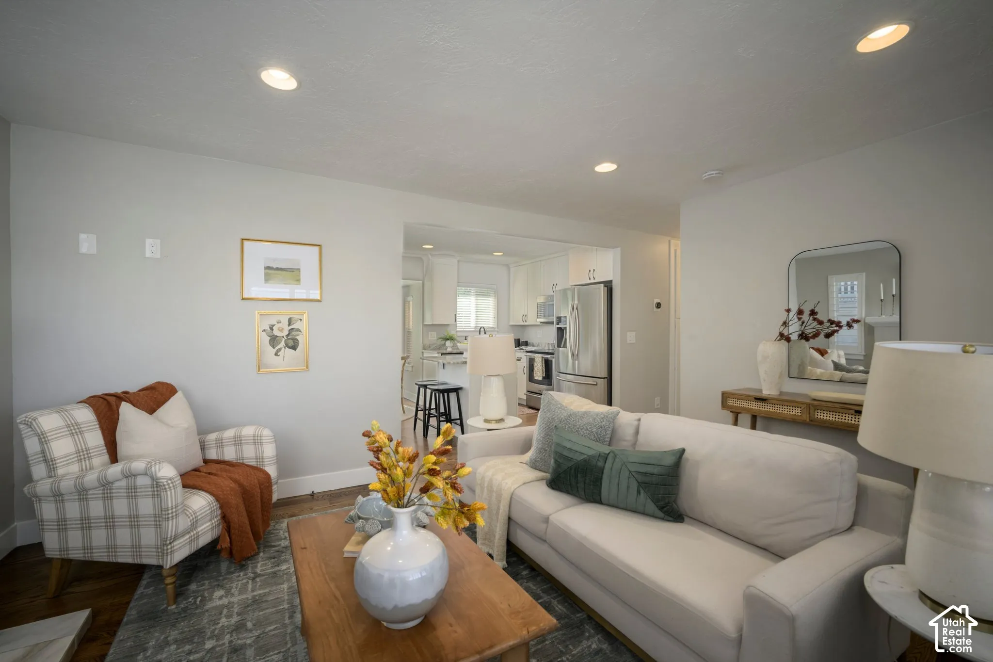Recessed ceiling lighting, light gray wall finishes, hardwood flooring, and a kitchen with stainless steel appliances
