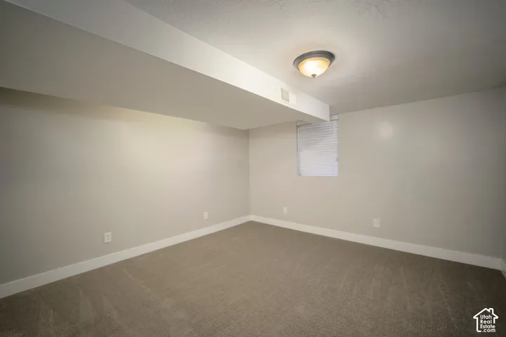 Recessed ceiling light fixture, neutral wall paint, carpeted flooring, window with blinds