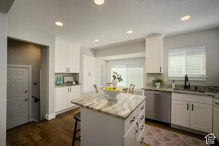 Kitchen featuring a central island with a granite countertop, white cabinetry with dark hardware, recessed lighting, and hardwood flooring