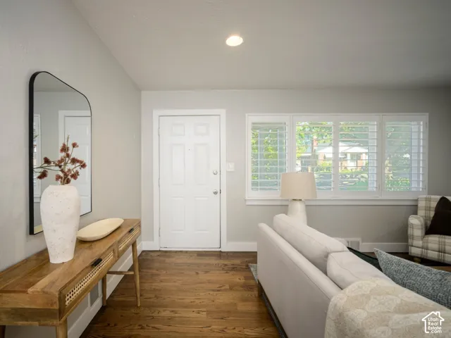 Hardwood flooring with a light gray wall finish, recessed lighting, and a window featuring white plantation shutters